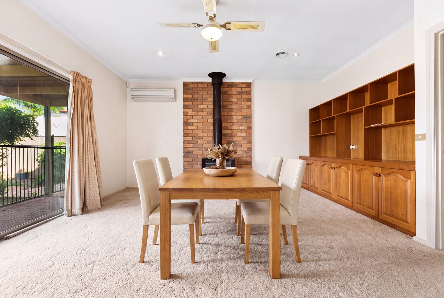 Family room with a wood heater, built-in timber cabinetry and sliding doors to the covered patio