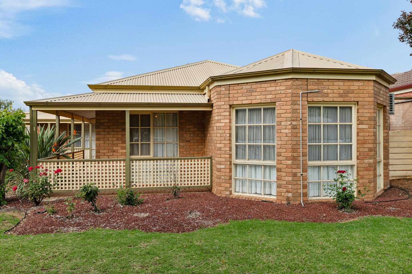 Brick frontage with a covered verandah, bay windows and garden